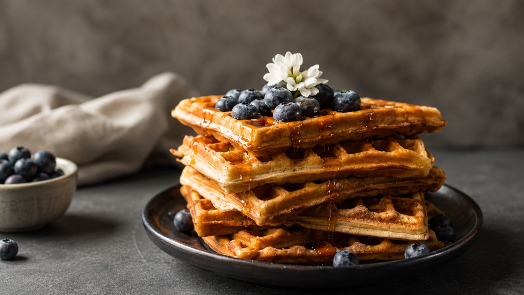 Freshly baked artisanal waffle stack with berries and maple syrup